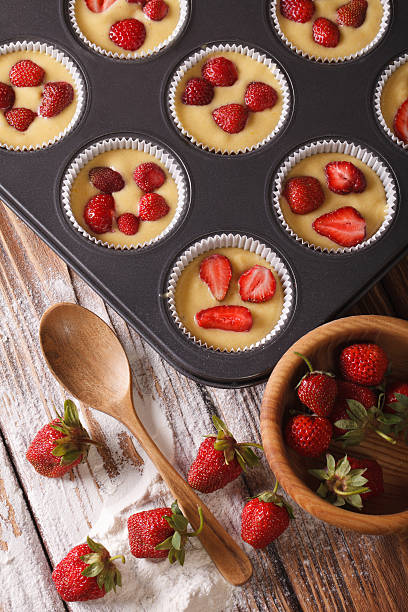 istock Preparation of muffins with fresh strawberries vertical top view 495581120