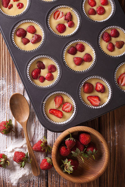 istock cooking muffins with fresh strawberries vertical top view 495588414