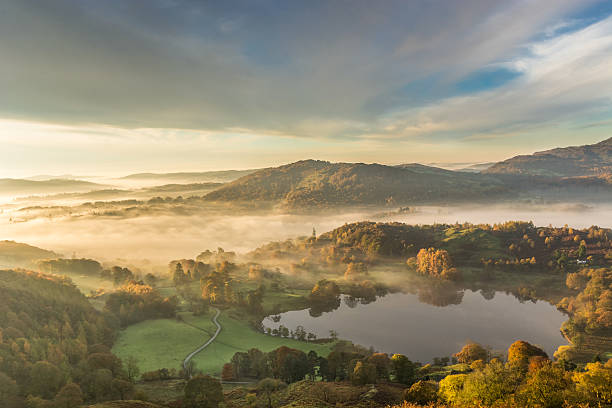 golden mattina luce attraverso vivi langdale nebbia nella valle. - uk mountain color image cumbria foto e immagini stock