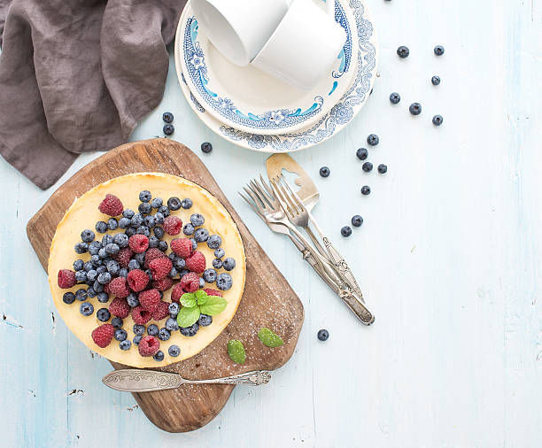 istock Cheesecake with fresh raspberries and blueberries on a wooden serving 495600254