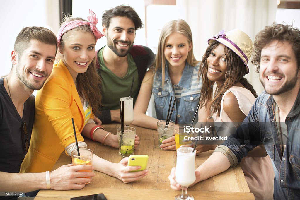 Friends having fun at the bar. Friends having fun at the bar outdoors, drinking cocktails and using smartphone. 20-29 Years Stock Photo