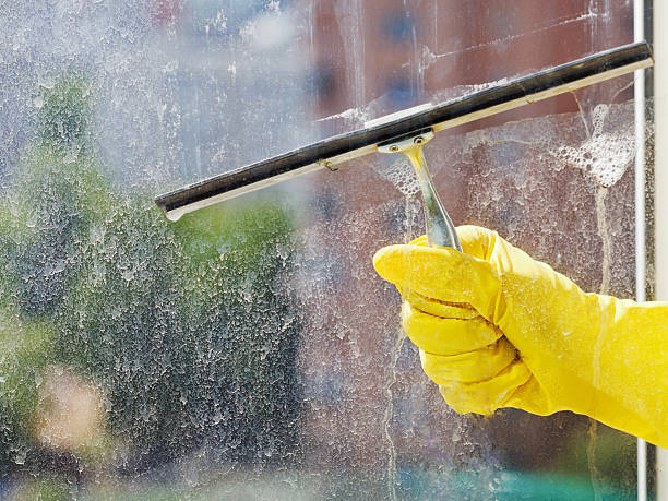 istock hand in yellow glove wiping window by squeegee 495603157