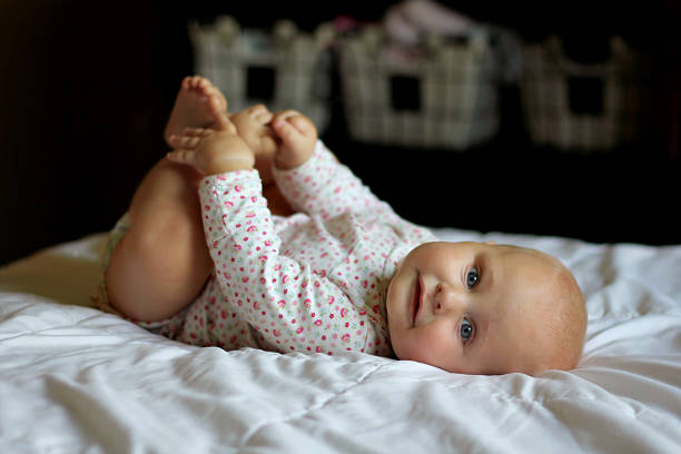 relaxante e bebê menina brincando com os dedos dos pés - 5 month old - fotografias e filmes do acervo