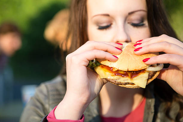 istock woman bites into a hamburger 495604273