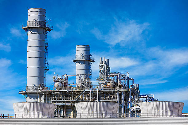 Natural Gas Fired Electrical Power Plant A natural gas fired turbine power plant with it's cooling towers rising into a blue sky filled with whispy clouds power station stock pictures, royalty-free photos & images