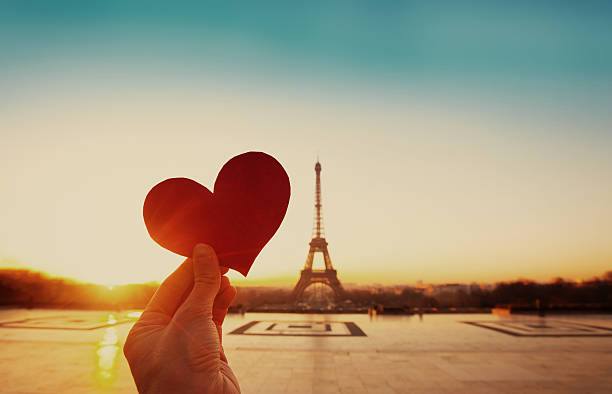 valentines day in Paris beautiful vintage card from Paris, Eiffel tower and hand with paper heart at sunrise valentines day holiday stock pictures, royalty-free photos & images