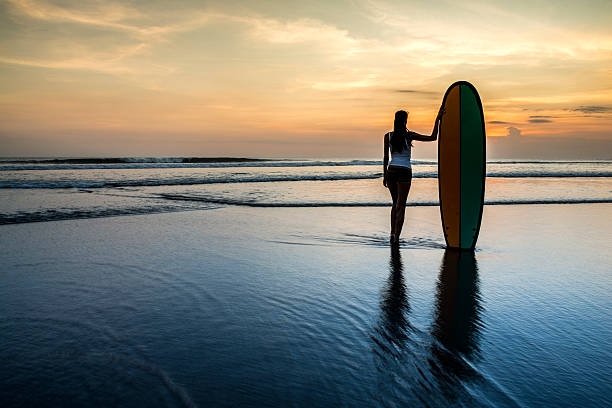 istock Woman with surf board on the beach at sunset 495609461