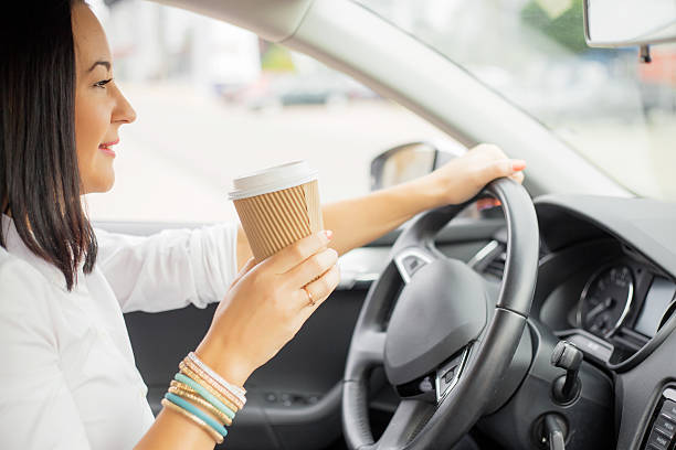istock Woman driving and holding a coffee cup 495614570