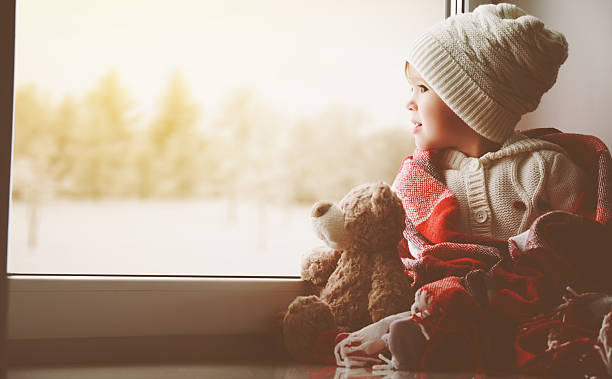 istock child little girl with  teddy bear at window 495616200