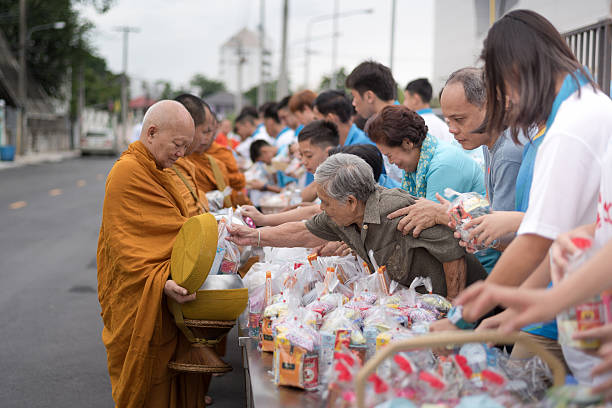 Giving Alms to Thai monk on Thai Mother Day occasion Bangkok, Thailand - August 12, 2015: Unidentified old woman in thai clothes Giving Alms to a Buddhist monk on Thai Mother Day. alms stock pictures, royalty-free photos & images