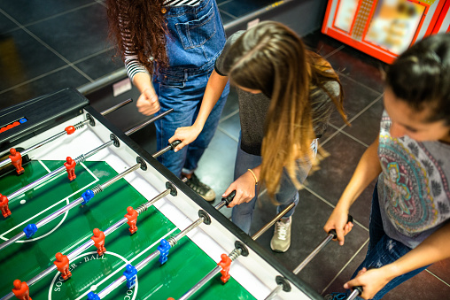 Friends have fun on the game room playing foosball