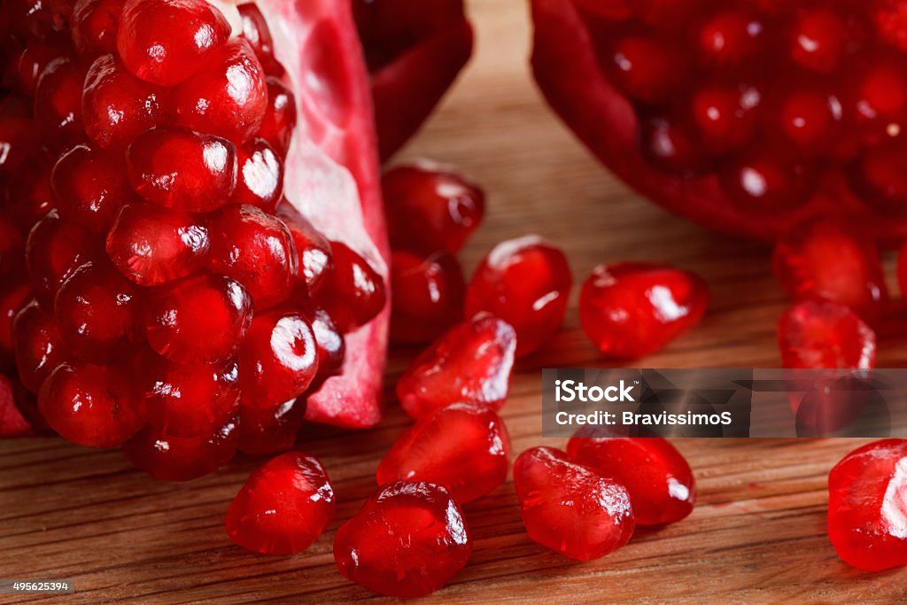 Ripe pomegranate seeds close-up on a cutting wooden board Ripe red pomegranate seeds close-up on a cutting wooden board 2015 Stock Photo