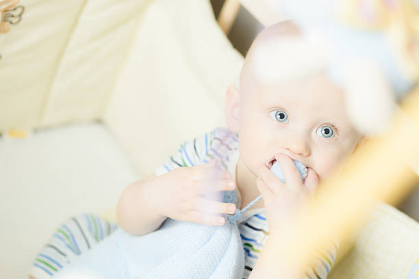 istock little baby biting his cap when sitting in childrens bed 495626211