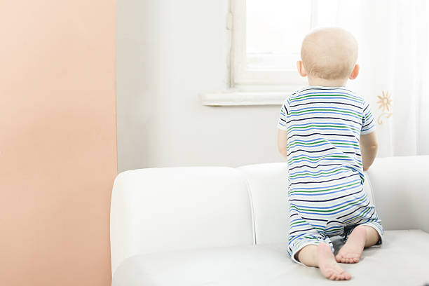 istock little baby  on  sofa and looks out the window 495626265