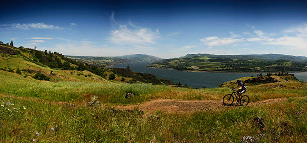 Bike Rider going uphill Mountain bike rider on Syncline trail with gorge view at a background, Columbia river, WA, Oregon, United States syncline stock pictures, royalty-free photos & images