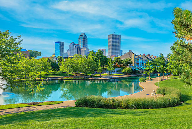 Skyscrapers of Indianapolis skyline, Indiana The Canal Walk lined with trees fills the foreground leading back to the main skyscrapers of Indianapolis skyline with whispy clouds in the sky, Indiana indianapolis photos stock pictures, royalty-free photos & images