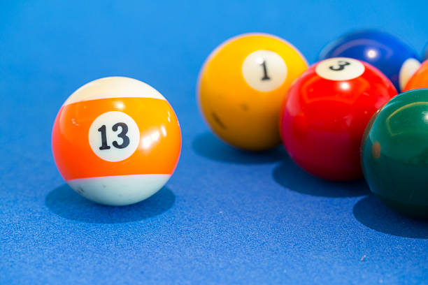 orange snooker ball with number thirteen on it with other colorful balls placed in a row on a table