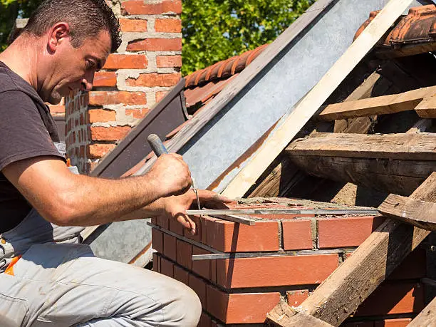 Man is measuring mortar thickness on chimney for new line of bricks on an old house in Ljubljana, Slovenia