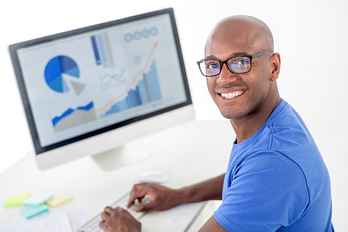 African American man working at the office and using a computer while wearing glasses - isolated over white