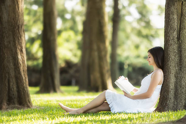 istock Relaxed, young woman reading book on green grass 495652079