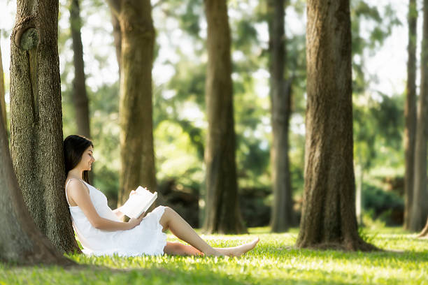 istock Relaxed, young woman reading book on green grass 495652085