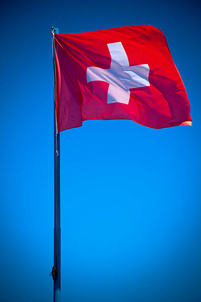 istock Swiss flag in front of bright blue sky 495652092