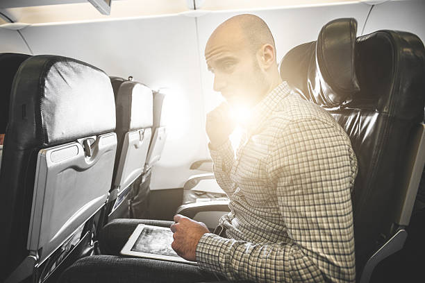 istock Pensive businessman working with digital tablet on the plane 495652463
