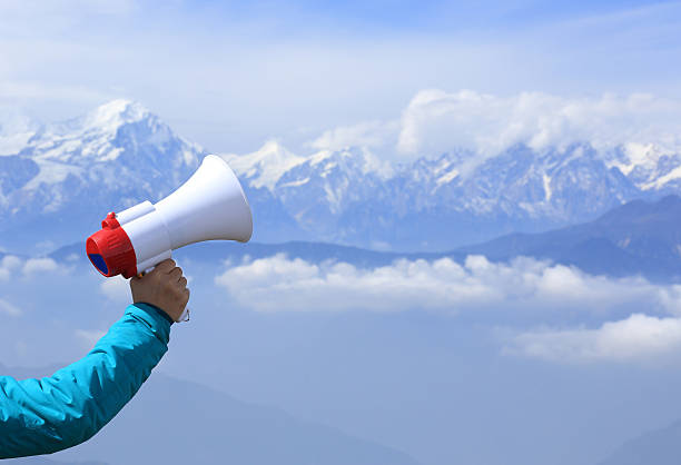 hand hold loudspeaker to blue sky on mountain peak