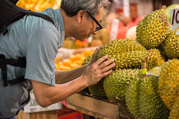 Asian Man Examining Durian Fruit at a Market stock photo