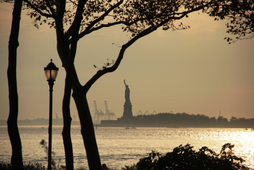 Battery park  in Manhattan with the statue of liberty in background in  a goldy t sunsetBattery park  in Manhattan with the statue of liberty in background in  a goldy t sunsetBattery park  in Manhattan with the statue of liberty in background in  a goldy t sunset