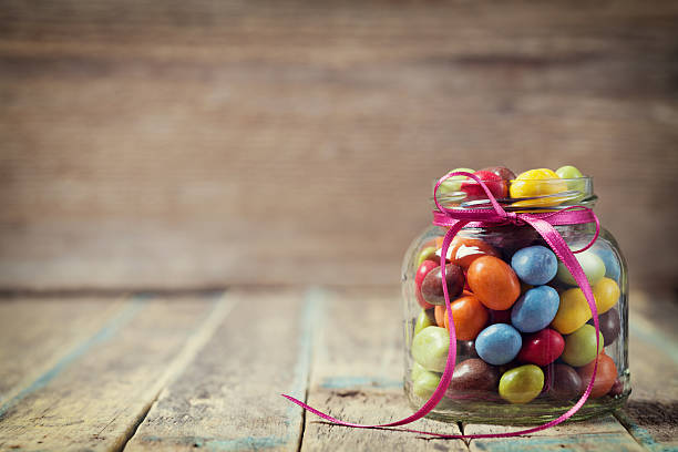 istock Candy jar decorated with a bow against rustic wooden background 495667408