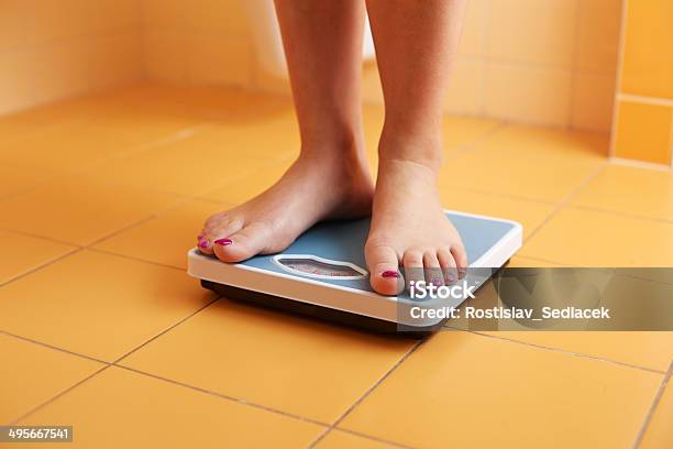 Pair Of Female Feet On A Bathroom Scale Stock Photo - Download Image Now - Weight Scale, Scale, Human Foot