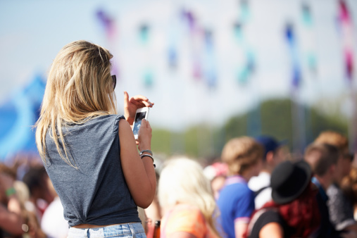 Young Woman At Outdoor Music Festival Using Mobile Phone Summer