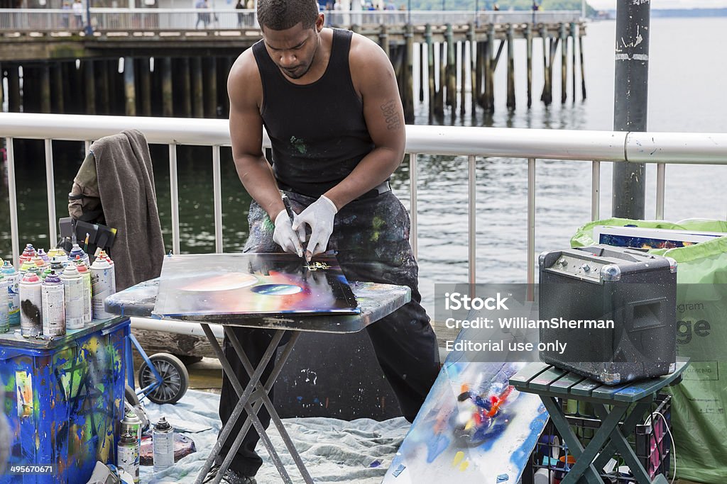 Spray Paint Artist in Seattle (Horizontal) Seattle Washington, USA - May 2, 2014:  A Seattle  street artist uses spray paint to create a surreal painting.  The street artist is working on Pier 57 on the waterfront of Elliott Bay.   Pier 57, where the artist is working, was built in 1902 and was also known as the Milwaukee Pier.  Horizontal orientation. Activity Stock Photo