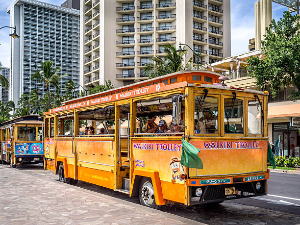 Waikiki Trolley bus Waikiki, HI, USA -April 29, 2014: Waikiki Trolley bus on Kalakaua avenue in Waikiki. The Waikiki Trolley bus is a popular shuttle bus that takes tourists around scenic Waikiki in Honolulu. trolley bus stock pictures, royalty-free photos & images