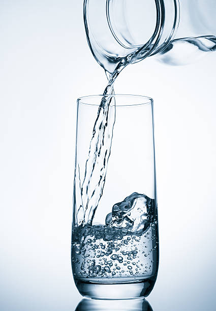 istock Pouring water from glass pitcher on blue background 495691545