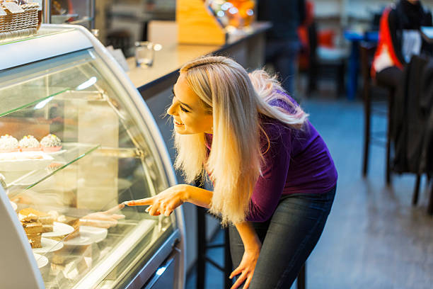 istock Cute young girl looking at display window with cakes 495691870