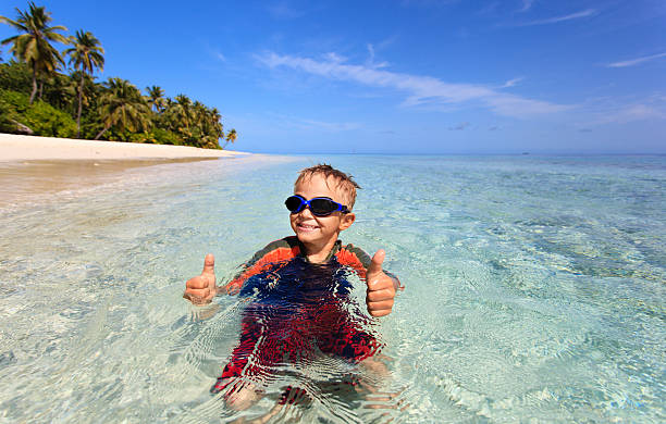 istock happy little boy swimming on tropical beach 495692836