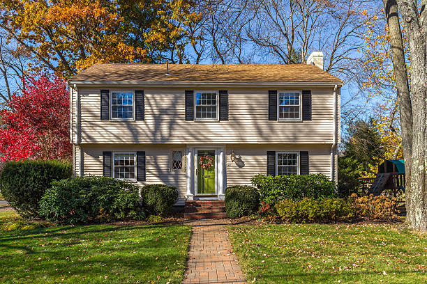 Colonial style New England Home. House Exterior Image of a Colonial House with yellow exterior in New England area. Landscaped front yard with grass and bushes is in foreground. Clear blue sky and trees are in background. colonial style photos stock pictures, royalty-free photos & images