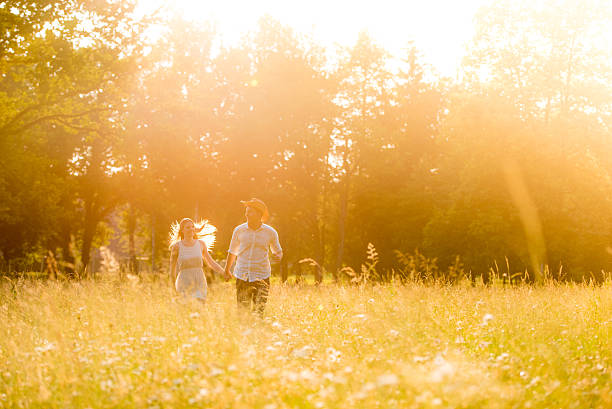 istock Young couple walking on meadow at sunset 495696572
