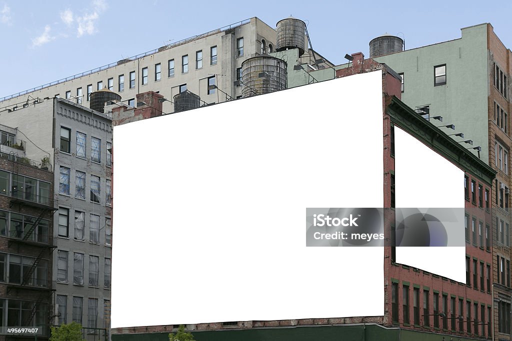 Two white blank billboard on the brick wall building. Two big, white, blank, billboard on the red brick building. On the roof visible water wooden tank. Billboard Stock Photo