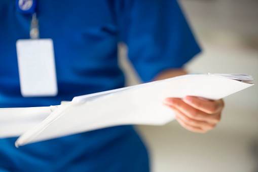 Unrecognizable nurse with medical report, selective focus 