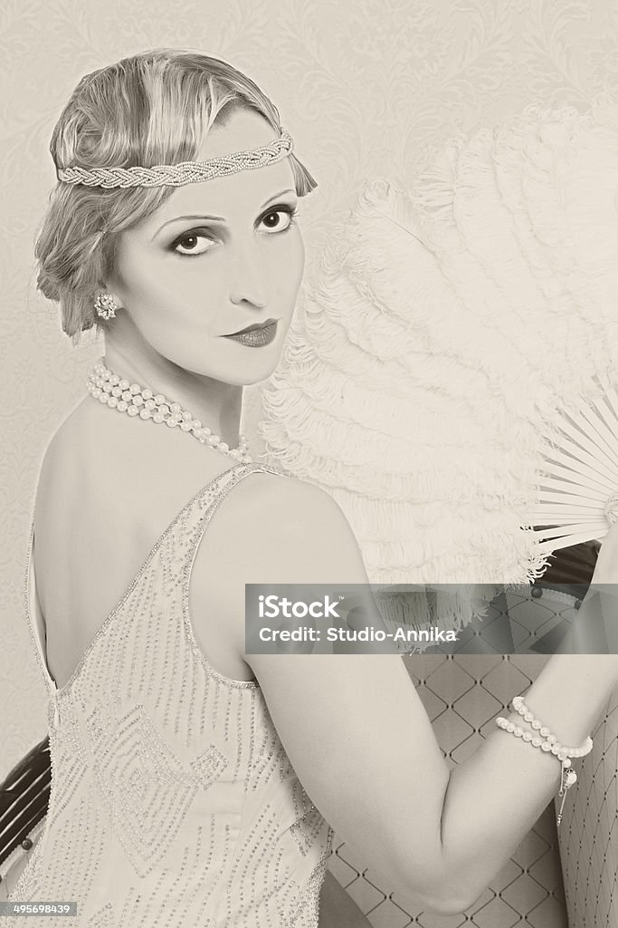 Old photo twenties style woman Old photo effect of a vintage twenties woman with feather fan Flapper Style Stock Photo