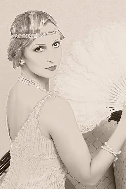 Old photo effect of a vintage twenties woman with feather fan