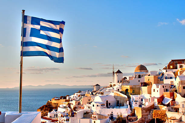 Greek Flag over Oia Digital photo of the Greek flag flying in Oia, Santorini aegean islands photos stock pictures, royalty-free photos & images