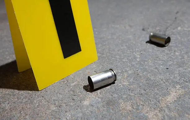 Evidence marker next to two empty handgun cartridges on concrete