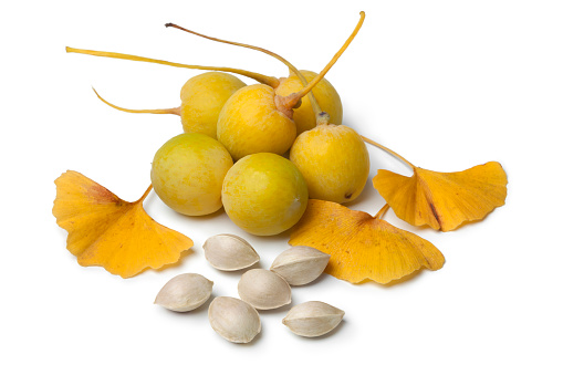 Ripe yellow Ginkgo biloba fruit, nuts and leaves on white background