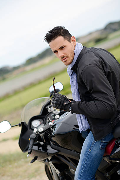 istock handsome young biker man riding a black motorbike 495715323