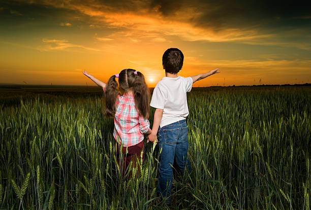 istock children in a field at sunset 495719845
