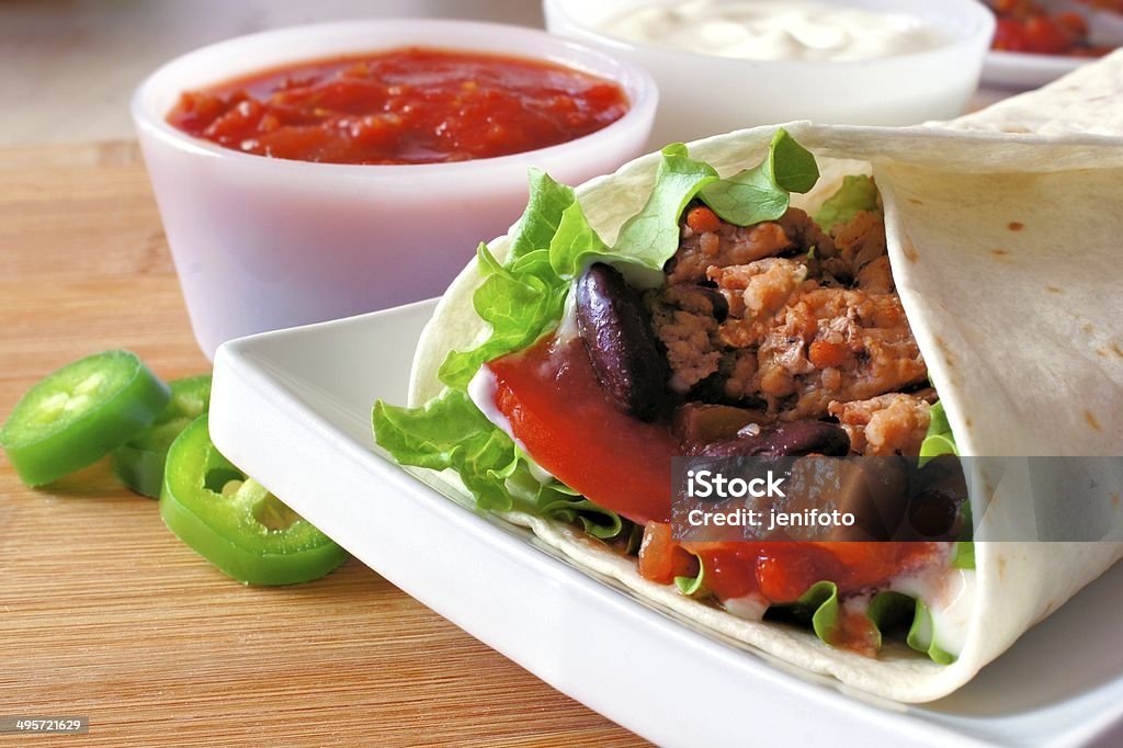 Meat and vegetable burrito on plate close up Close up of a burrito on a plate filled with meat and vegetables Appetizer Stock Photo